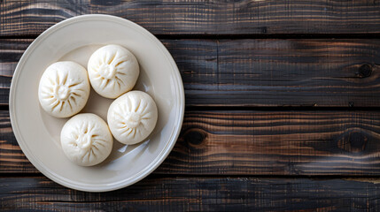 Four steamed bao buns resting on a plate, served on a dark wooden table, providing a simple and elegant culinary backdrop
