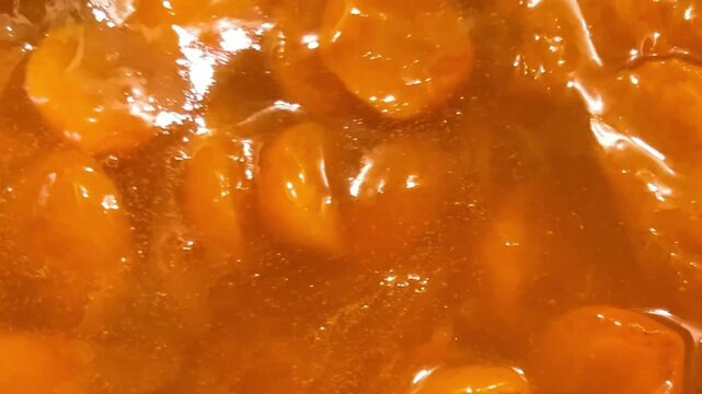 The process of making apricot jam in a metal pan. The jam is cooked in a pan.