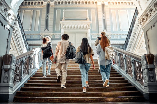 A group of college students walking up the stairs with backpacks on their shoulders. Motivation and academic success.Copy space. - Powered by Adobe