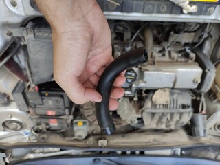 Man holding car engine pipe in hand against car engine background