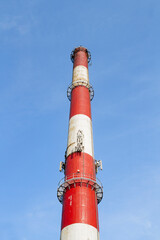 An industrial chimney against a clear sky, painted white and red | Komin przemysłowy na tle czystego nieba, pomalowany na biało-czerwono