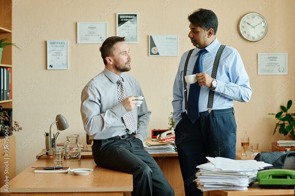 Poster two businessmen in office setting holding cups and having conversation about business strategies whi