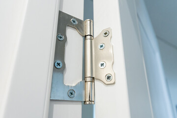 A highquality, durable stainless steel hinge is expertly attached to a sleek, modern white door,...