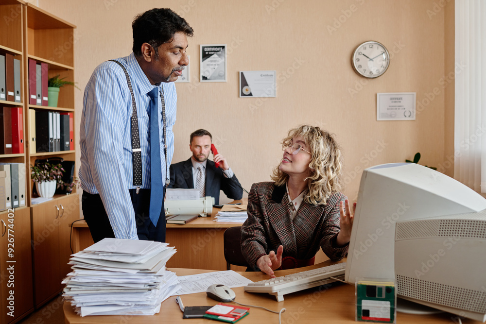 Poster Three business professionals working in office with documents and desktop computer surrounding them, conversing about important matters and strategizing office workflow