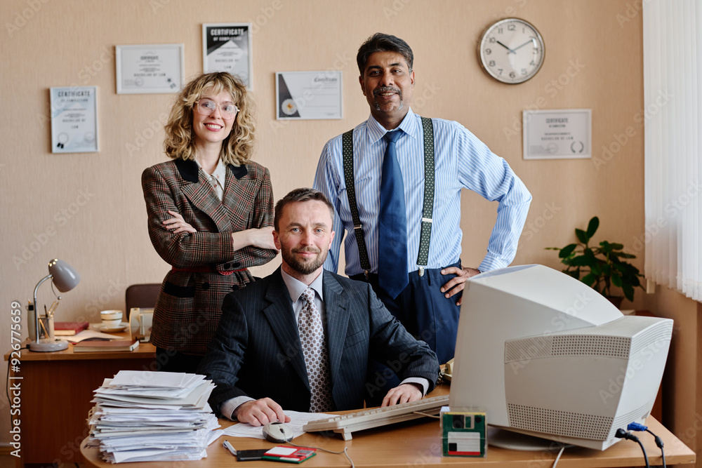 Poster group of three business professionals in an office, with certificates on wall, computer and paperwor