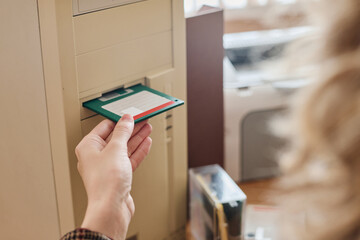 Hand inserting floppy disk into vintage computer drive slot, capturing nostalgic moment of early computer technology, showcasing outdated data storage methods