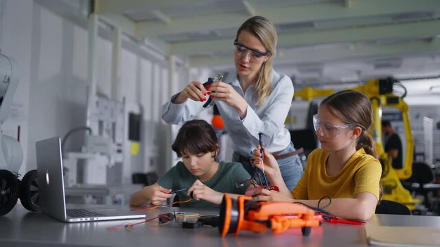 Children learning robotics in Elementary school. Young students building robot in after school robotics club. Field trip to real robotics laboratory.