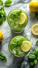 Refreshing green lemonade with fresh basil and lemon slices on marble table