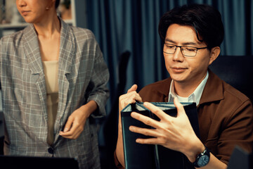 Managers discussing on document paperwork together for business planning on market share data at over late night time at modern home office, working on startup company deadline project job. Infobahn.