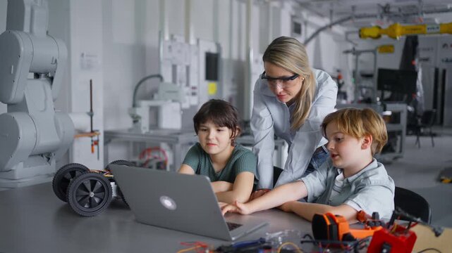 Children learning robotics in Elementary school. Young students programming, building robot in after school robotics club. Field trip to real robotics laboratory.