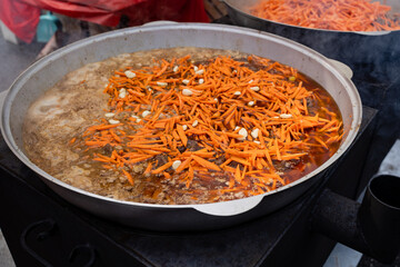 Making a Traditional Dish with Fresh Carrots in a Large Outdoor Pot, Emphasizing Artisan Techniques and Community