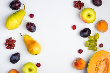 A variety of fruits, melon, apple, pear, grapes and peach on a light background. Composition of fruits. Top view, horizontal.