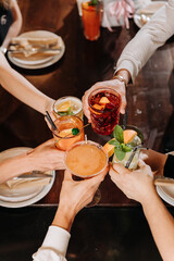 Top view of friends toasting with colorful cocktails at a lively gathering, celebrating togetherness