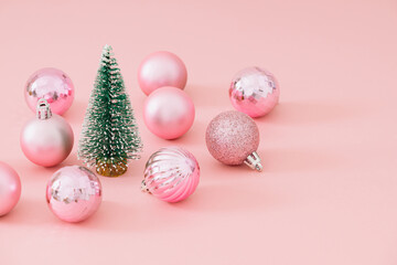 Christmas composition made with green Christmas tree and pink Xmas baubles on pastel pink background. Minimal Christmas and New Year concept. Creative festive holiday layout.
