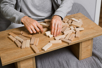 Man player balances wooden blocks, trying not to topple the tower in a competitive game setting