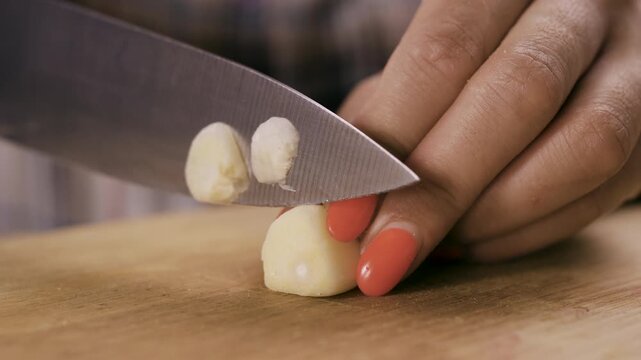 Close-up of woman cutting fresh garlic at wooden table