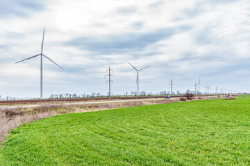 Wind turbines generating electricity in a green field. Green power generation concept.