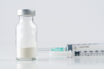 Vaccine vial glass with a syringe on white background.