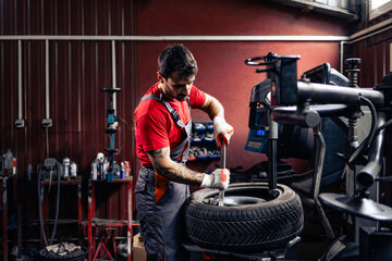 Hardworking service technician removing damaged tire from the wheel on machine.