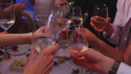 Group of guests celebrate and raise glasses, cheering with alcohol glasses with wine and champagne in the restaurant on corporate christmas birthday party event or wedding celebration, luxury event
