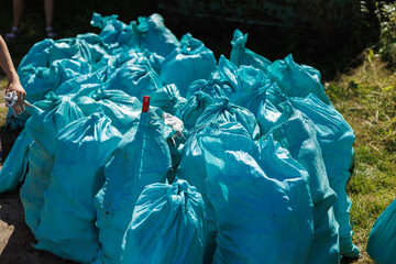 A large pile of bright blue garbage bags carelessly sitting on the ground, creating an eyecatching...