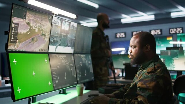 Air force officer performing tactical level surveillance in command room using mockup screen. Military specialist using radar on chroma key gear to look at assault zones, camera B