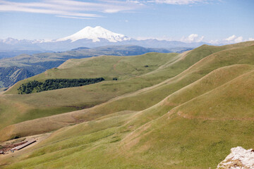 Naklejka premium A large mountain that is abundant with lush green grass and numerous trees growing all over its slopes and rocky surfaces
