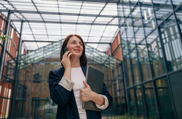 A professional businesswoman is having a phone conversation in a modern office setting