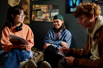 Group of young adults engaging in conversation about various artworks displayed on walls. Casual atmosphere with dialogue fostering creativity and collaboration