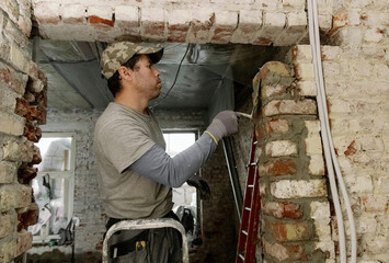 A young man places bricks in a doorway.