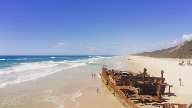 Drone, shipwreck and beach with people on sand for traveling, vacation and adventure on Fraser Island. Person, together and holiday for summer with walk on shore to check, explore or inspect site