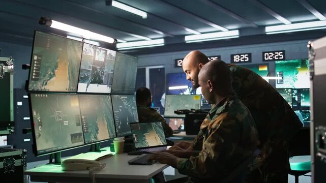 Military soldier in mission control center, overseeing national safety operations using notebook next to colleague. Team of army specialists examining data in monitoring room command center, camera B