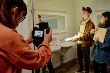 Several people are working on a film set with various equipment in a bathroom environment holding a...