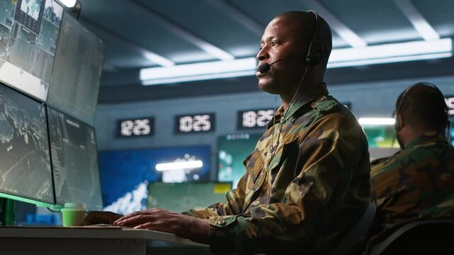 Army specialist working in war room operating surveillance tech, evaluating target data, talking in voice call. Dispatcher keeping in touch with allied troops engaging enemy forces, camera A