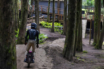 EUC vehicle rider navigating a dirt bike trail through trees in an outdoor park on a sunny day © Wanderson