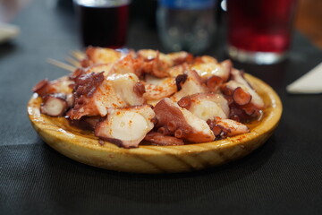 Typical feira octopus served on a wooden plate and with accompanying wine and bread.