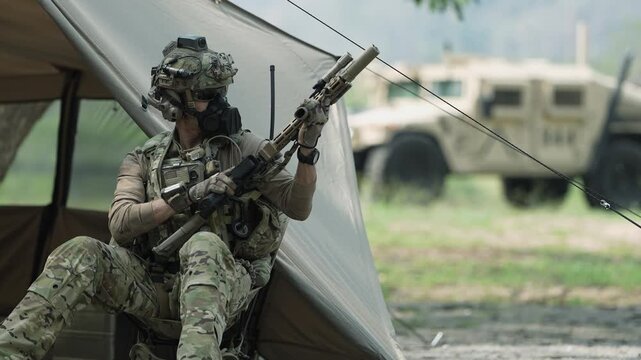 A group of military men in combat gear patrol in the middle of a desert and tropical jungle. Soldiers in full combat gear in dry weather conditions assemble and march on a mission.