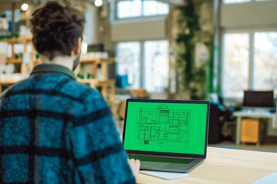 Architect presenting a project on a green screen laptop in an office.