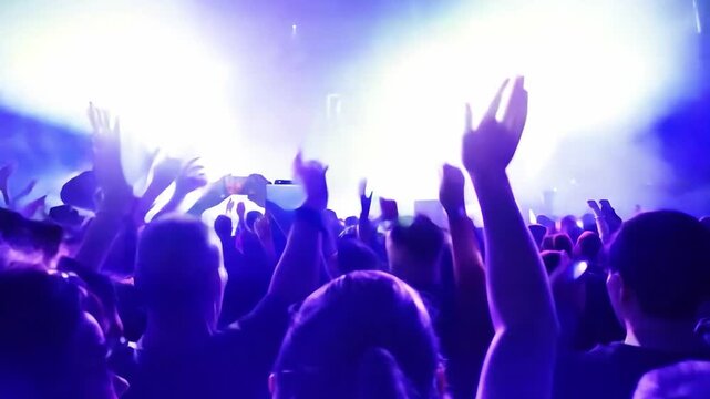 Crowd cheering and waving at music concert with lightshow