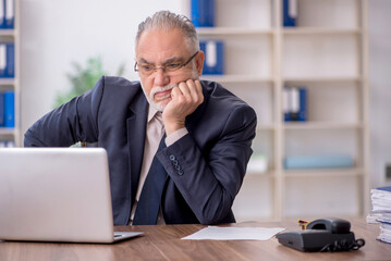 Fototapeta premium Old male employee working in the office
