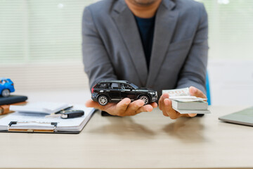 Asian business professional in a formal suit works at a desk, reviewing financial charts. manage car insurance claims, analyze auto loan options, sign lease agreements for vehicle transactions.