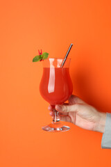Woman with glass of refreshing cocktail on orange background, closeup