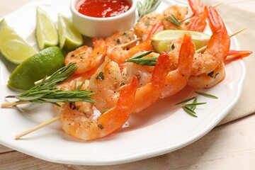 Skewers with delicious grilled shrimps served on wooden table, closeup