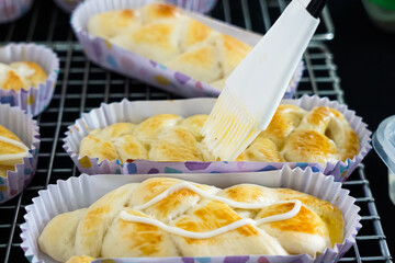 Hand brushing mayonnaise on breads before putting chicken floss
