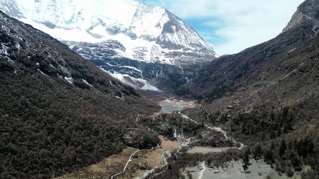 Drone shot of the scenic and breathtaking Yading nature reserve luorong pasture towards Lake Gongga with Mount Yangmaiyong in background. Situated in Sichuan, China.