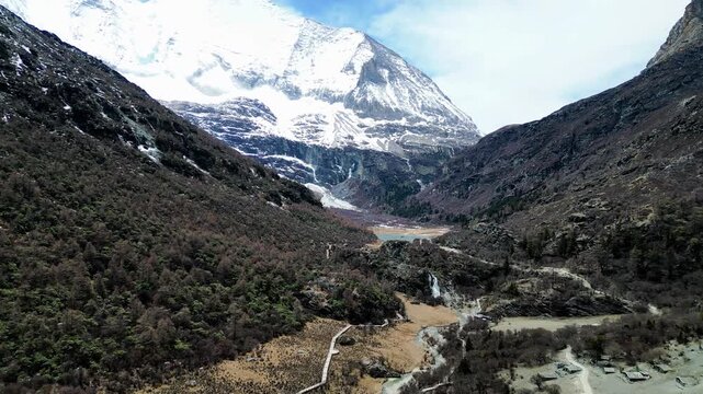 Drone shot of the scenic and breathtaking Yading nature reserve luorong pasture towards Lake Gongga with Mount Yangmaiyong in background. Situated in Sichuan, China.