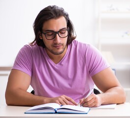 Young male student preparing for exams at classroom