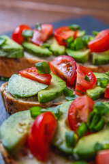 Avocado toast topped with tomato and green onion on a slice of carrot bread