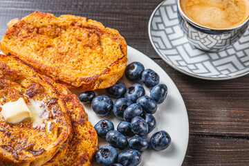 French toast on a white plate with blueberries and coffee for breakfast