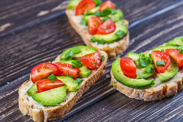 Avocado toast topped with tomato and green onion on a slice of carrot bread